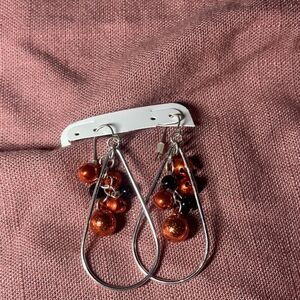 Silver tone with red bells dangle earrings.